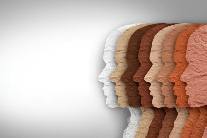 Row of crumpled paper head silhouettes in various skin tones aligned side by side against a white background