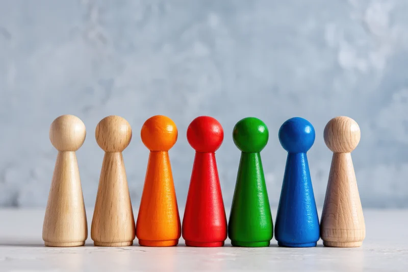 Row of colorful wooden peg dolls arranged in a line on a light surface