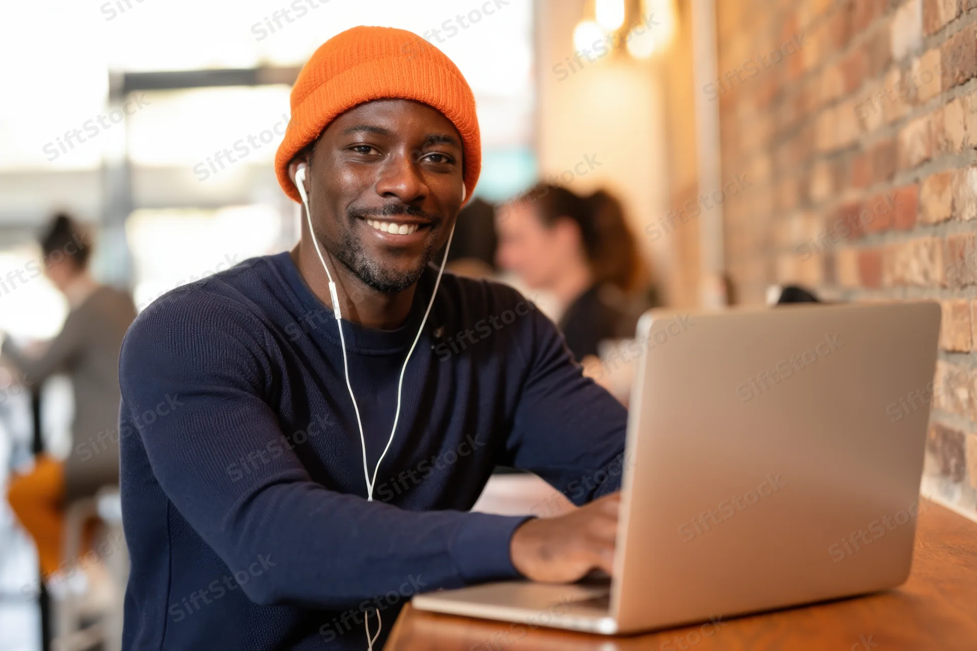 Young man smiling while using laptop at cafe table