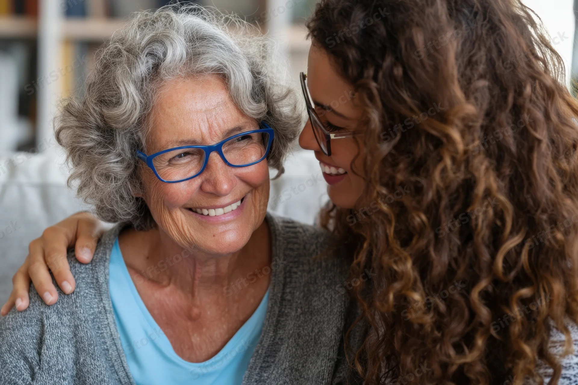 Senior woman smiling at her daughter on a living room sofa