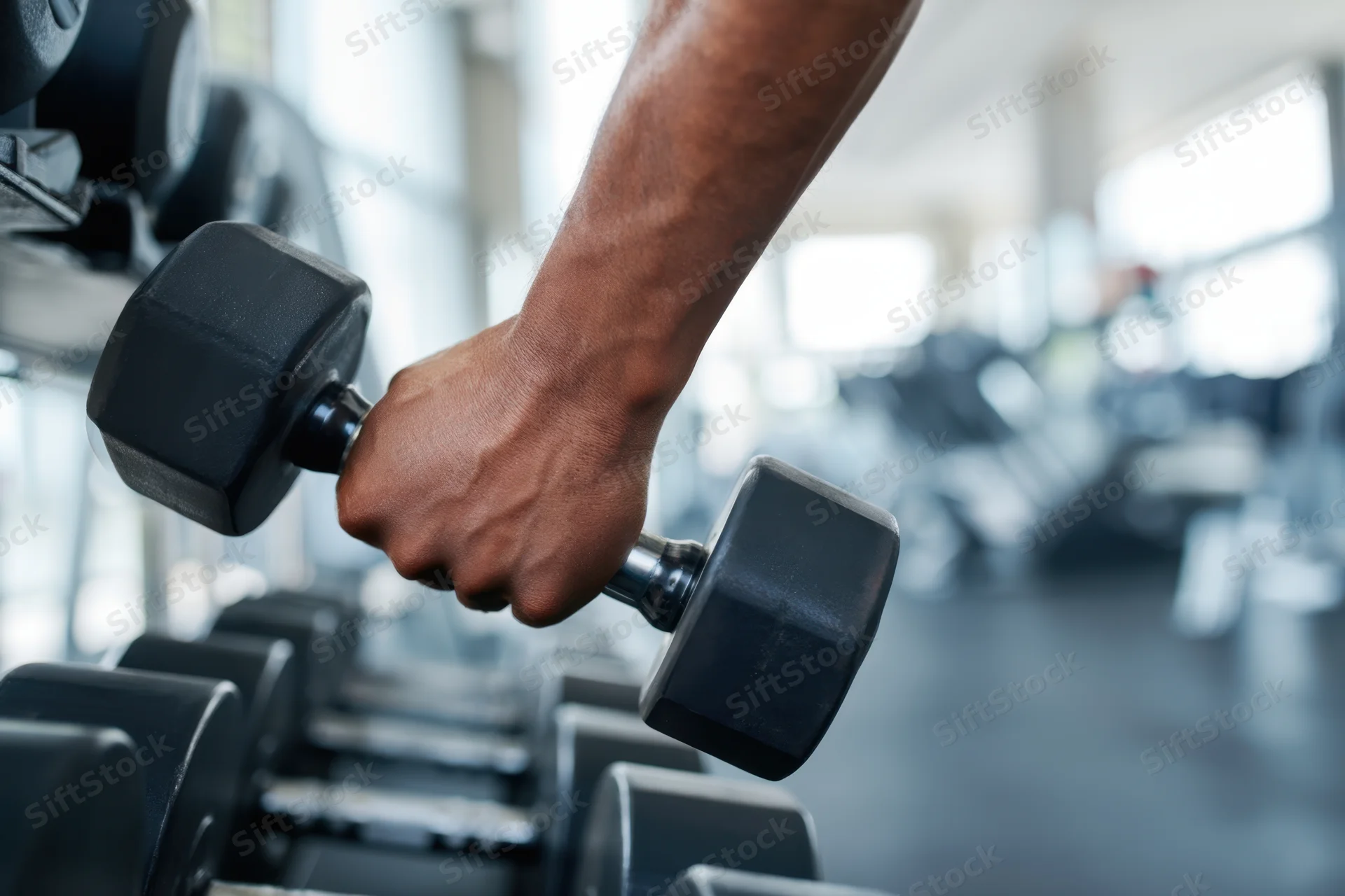 Close-up of a muscular arm gripping a dumbbell in a gym