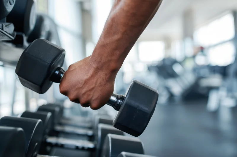 Close-up of a muscular arm gripping a dumbbell in a gym