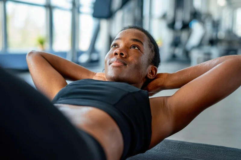 Woman doing crunches on exercise mat in gym