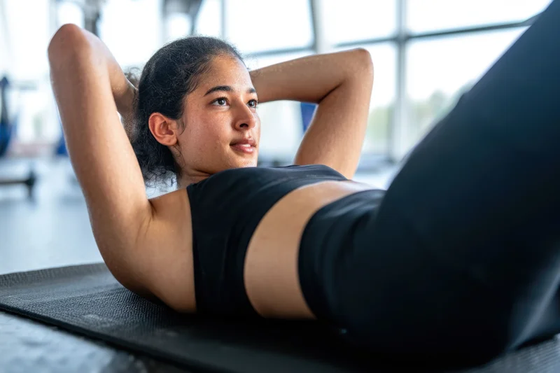 Woman doing abdominal exercises on a mat in a gym