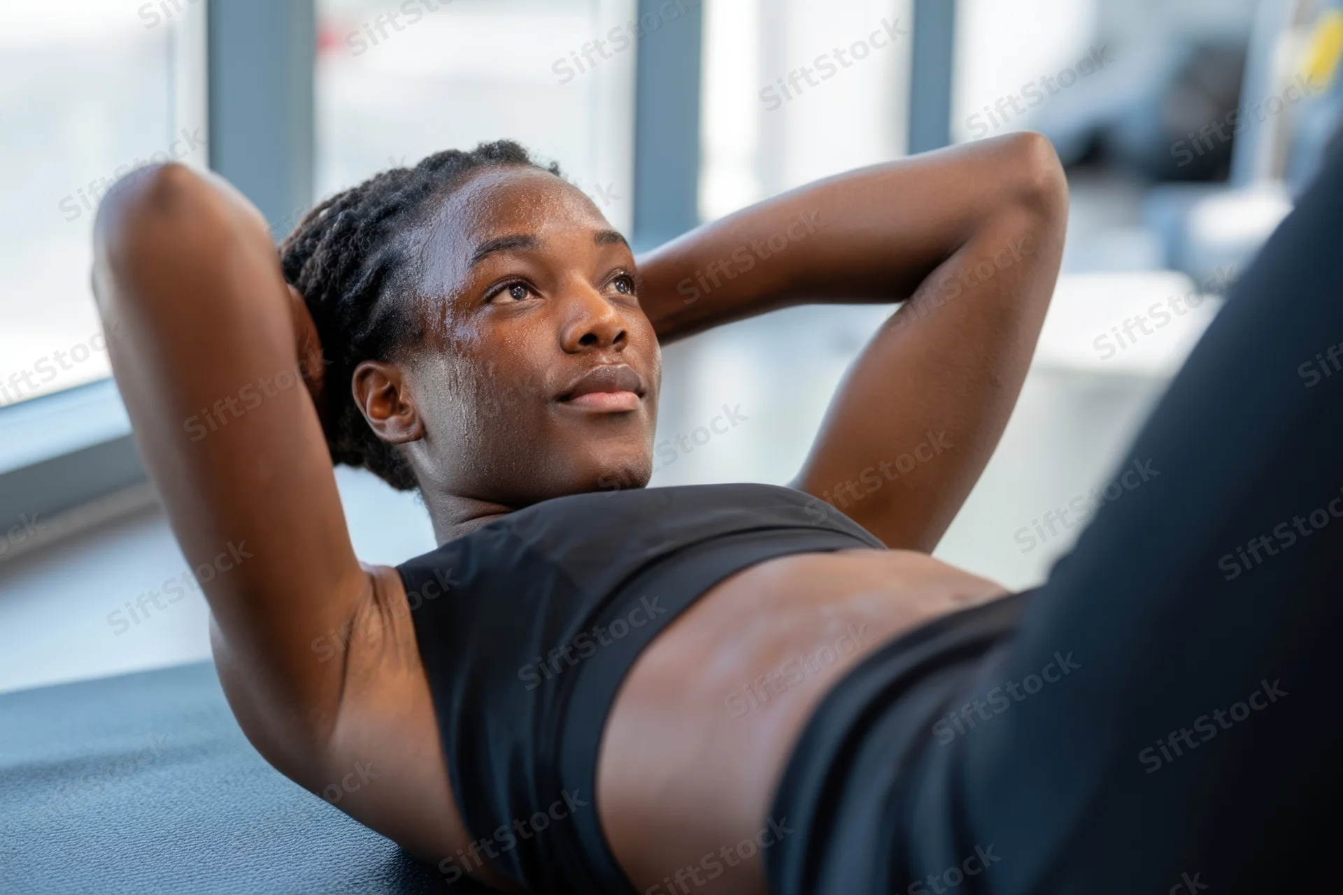 Woman doing crunches on exercise mat in gym