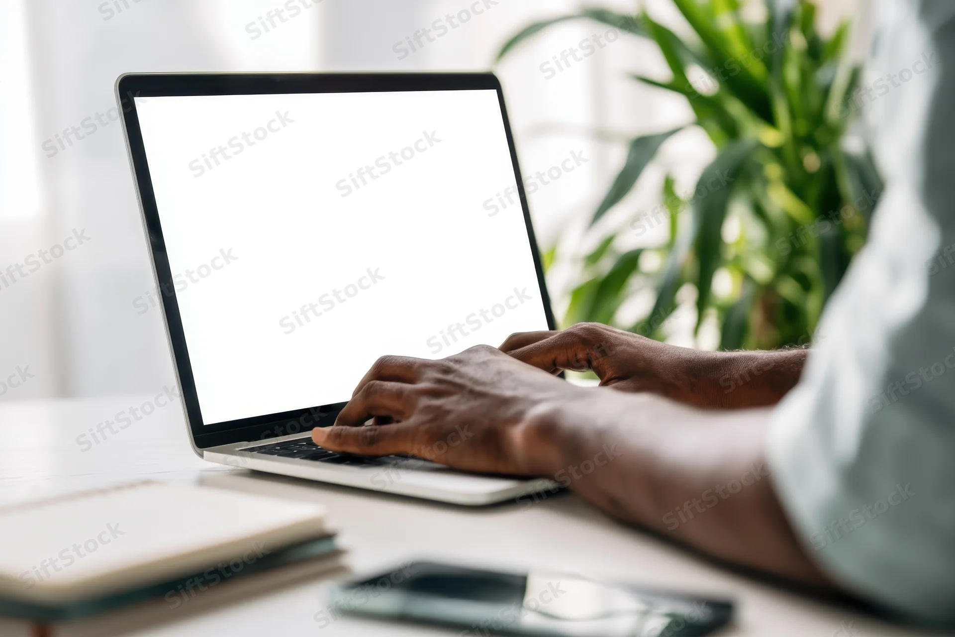 Man typing on slim laptop with blank white screen at home office desk