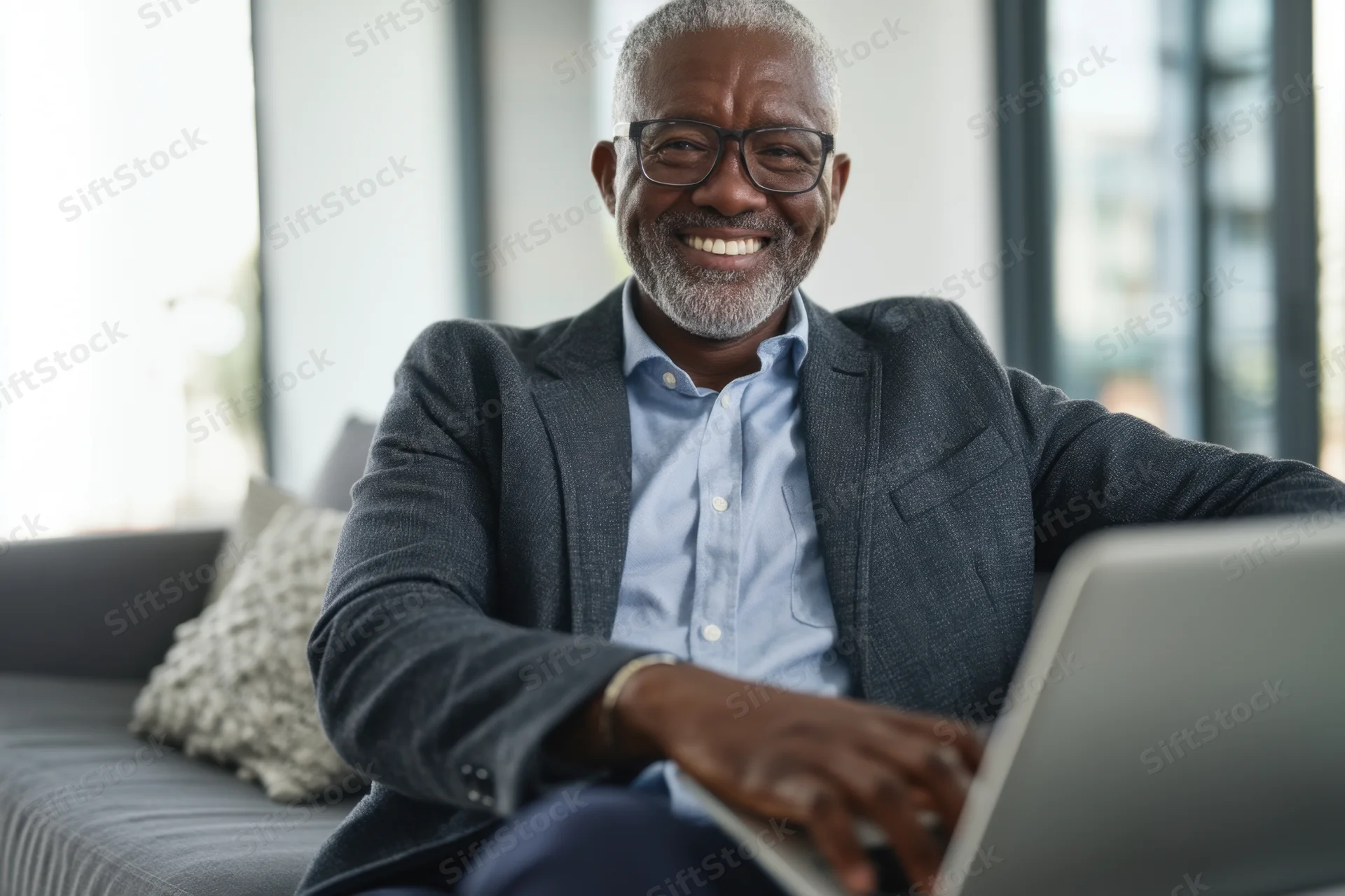 Smiling man using laptop on couch in home office