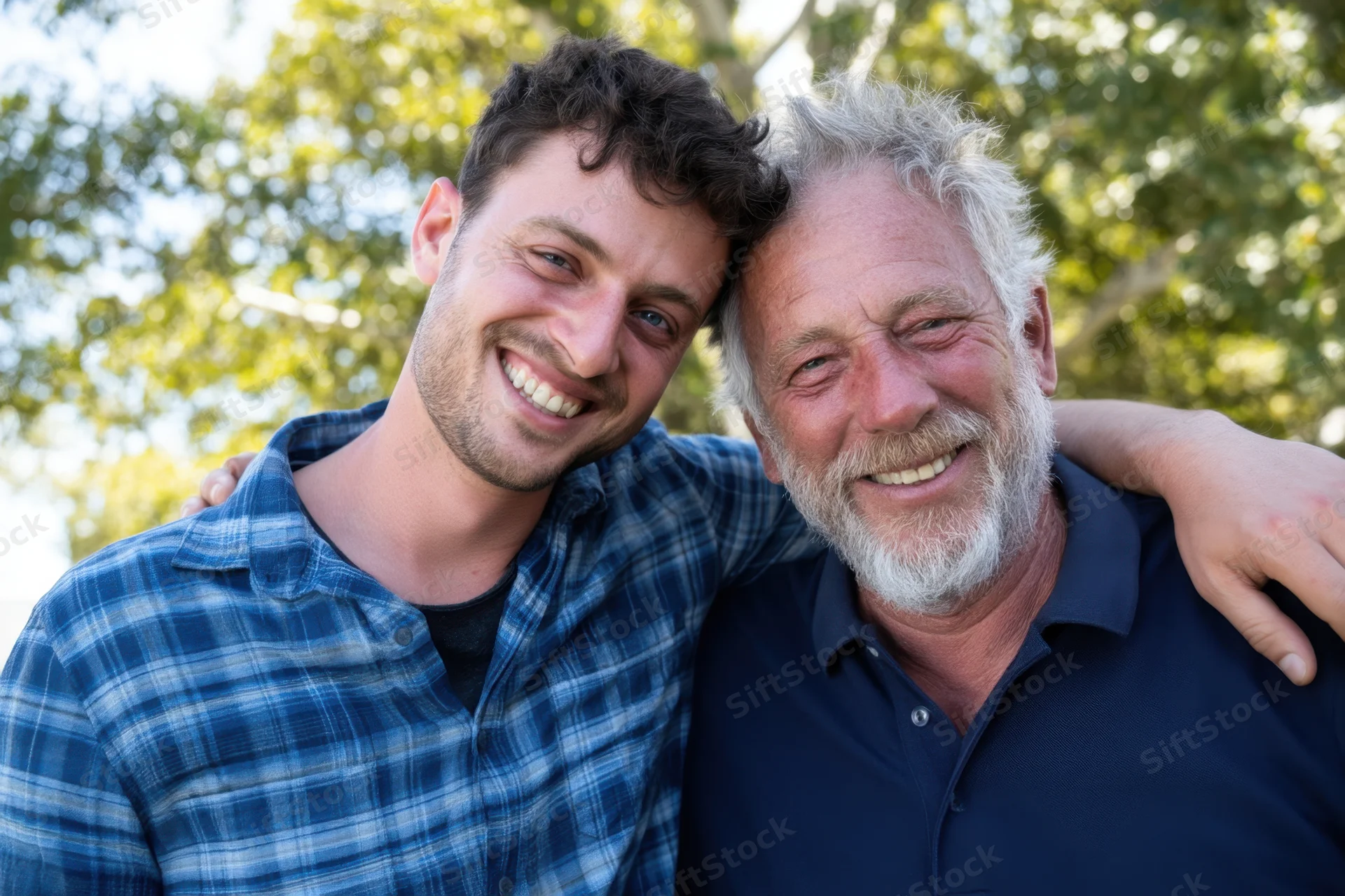 Younger man and older man smiling together outdoors with arms around each other
