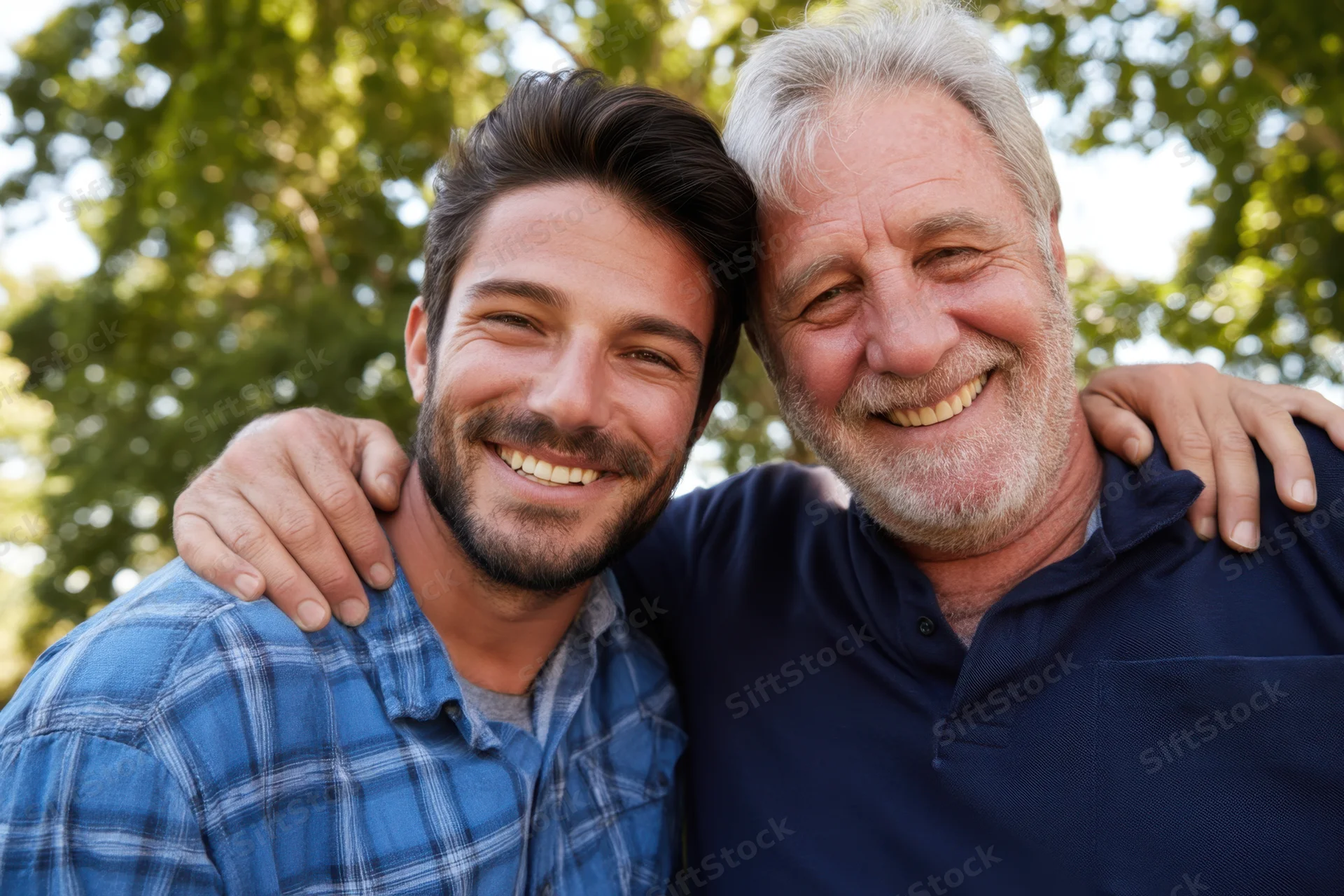 Father and son smiling together outdoors with arms around each other