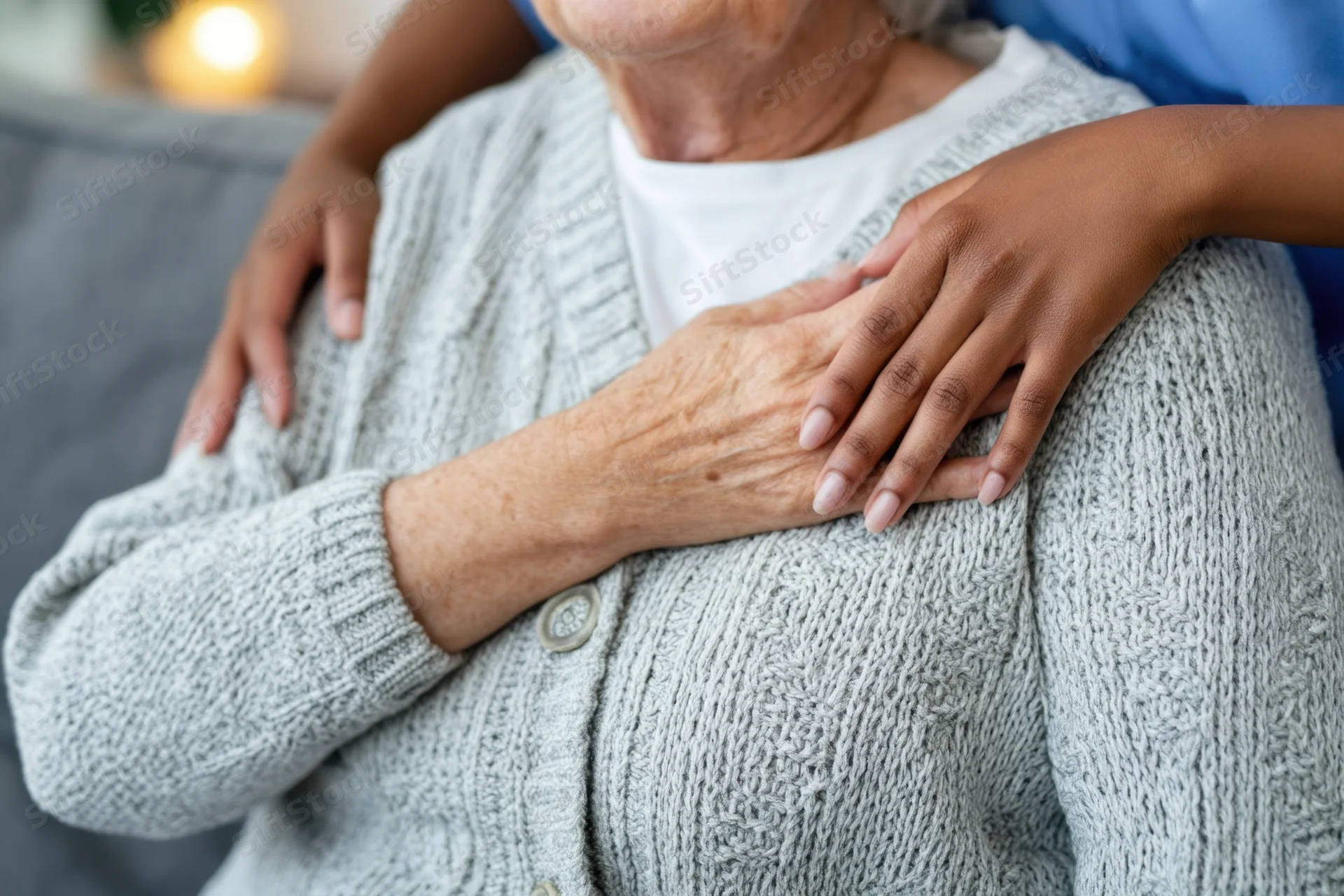 Elderly woman receiving comforting touch from another person on a couch