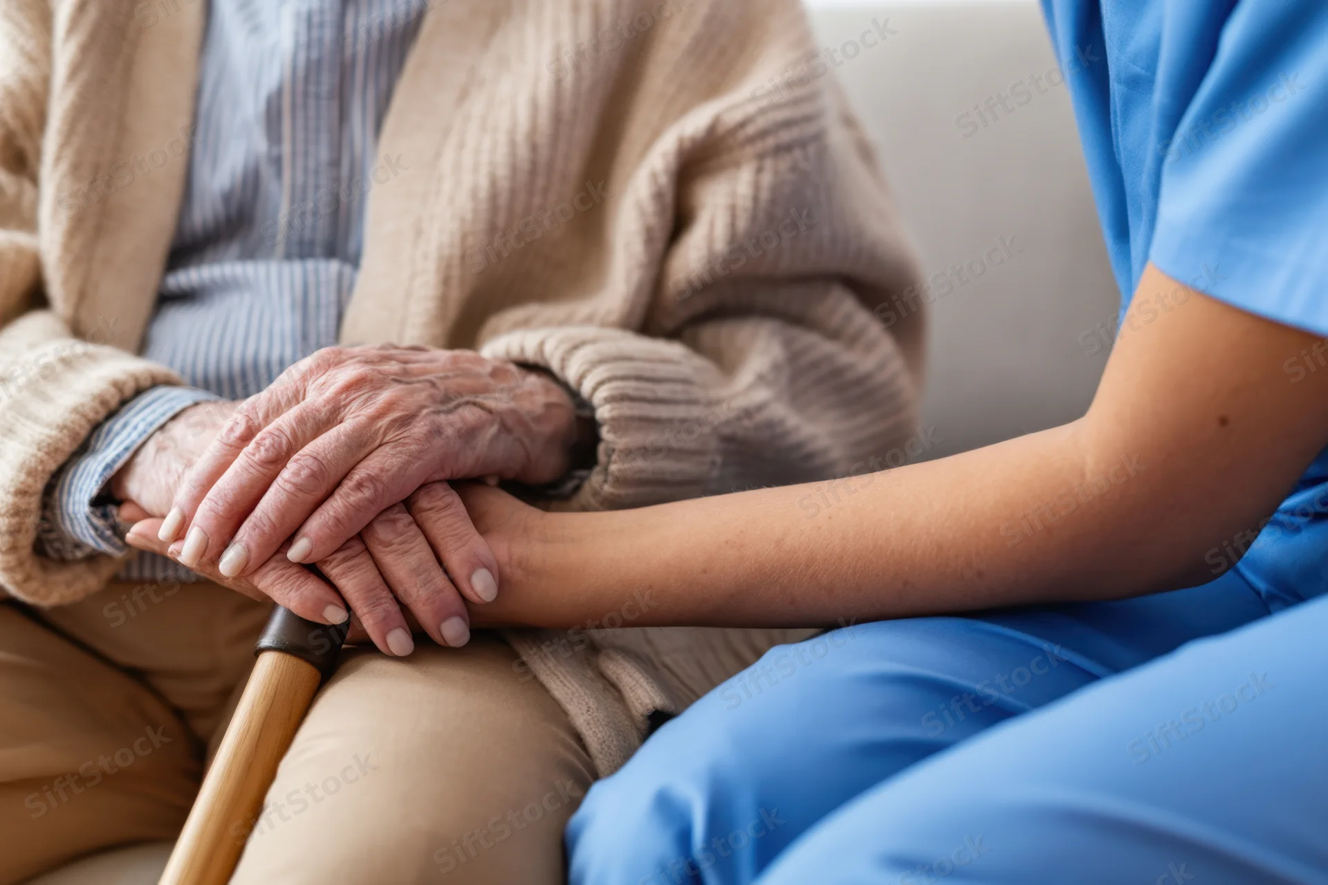 Elderly woman holding hands with caregiver in home setting