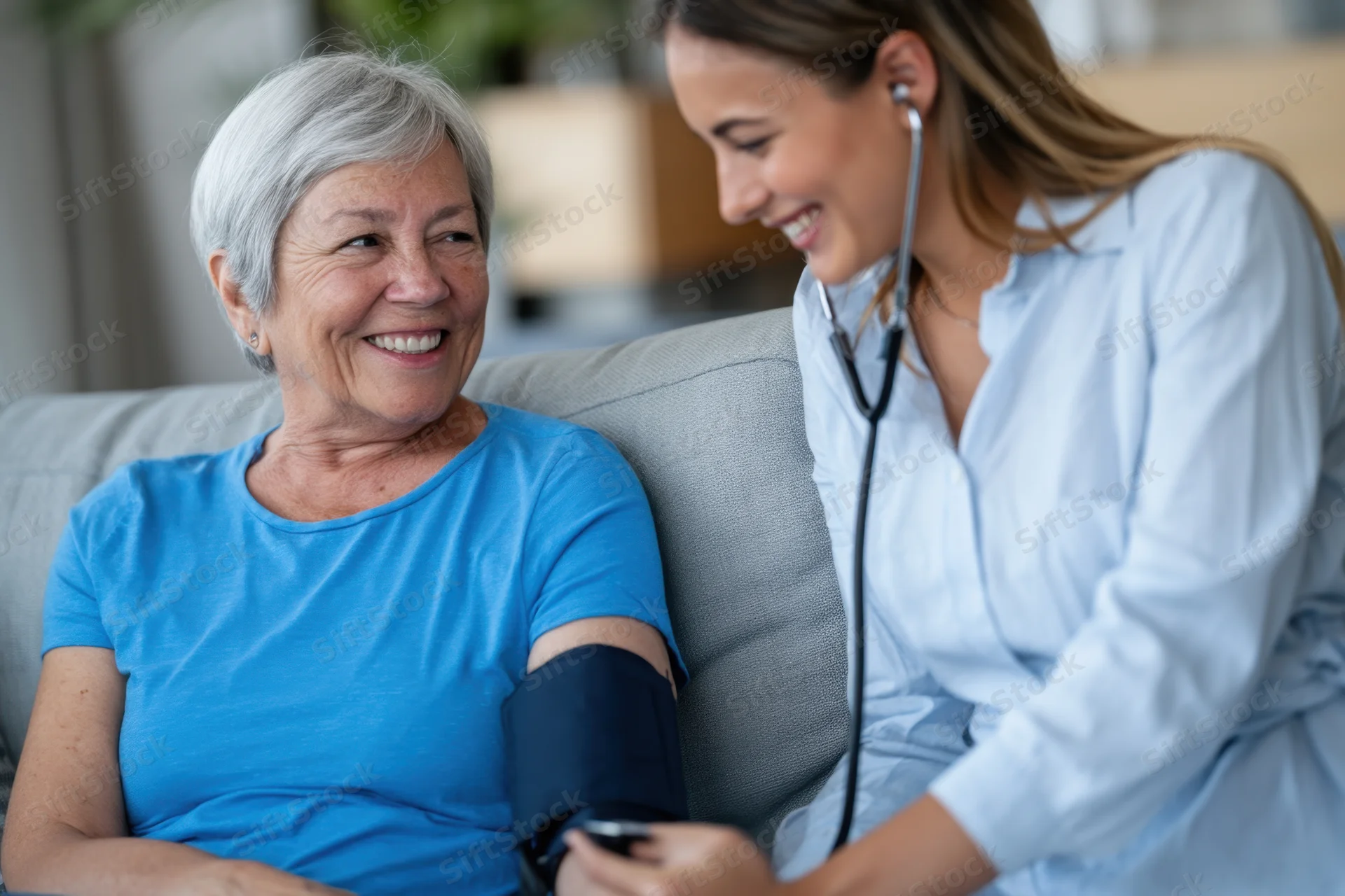 Senior woman smiling during blood pressure check by nurse in living room
