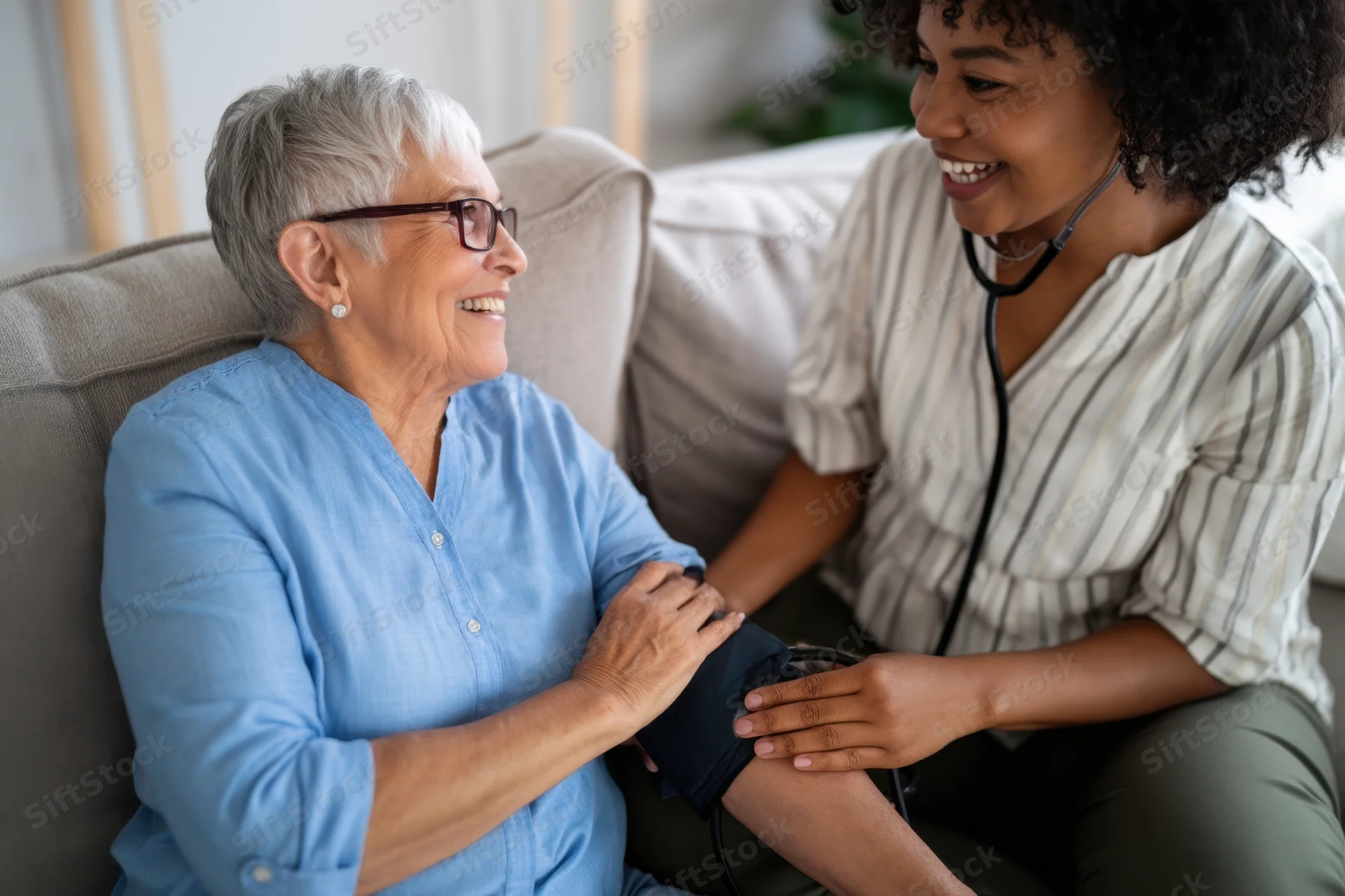 Senior woman receiving blood pressure check from nurse in home setting