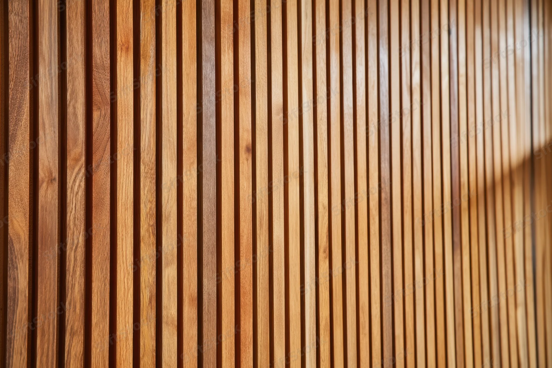 Vertical wooden slats arranged in a warm brown textured paneling for interior design