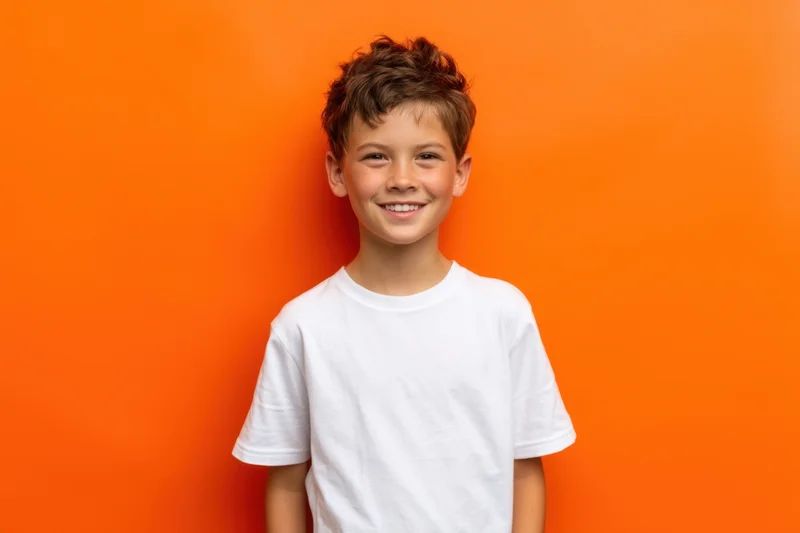 Young boy smiling in white tshirt against orange backdrop