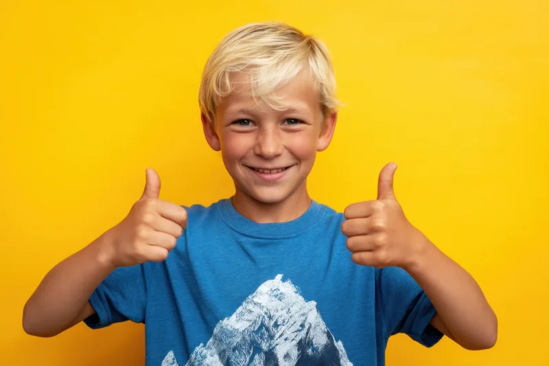 Young boy giving two thumbs up against yellow background