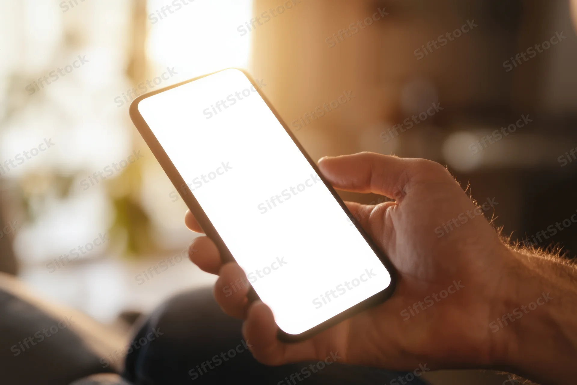 Hand holding smartphone with bright white screen indoors