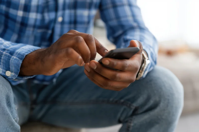 Man texting on smartphone while sitting in casual clothing at home