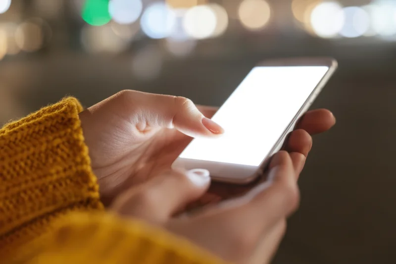 Hands holding a smartphone with glowing screen in a blurred urban night setting