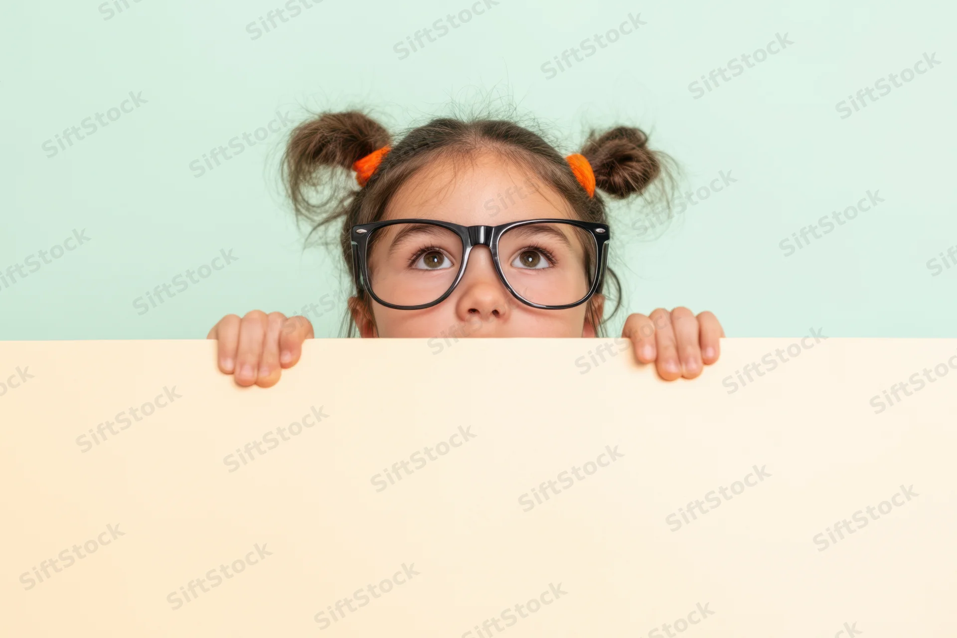 Young girl with oversized glasses peeking over a pale board in studio setting