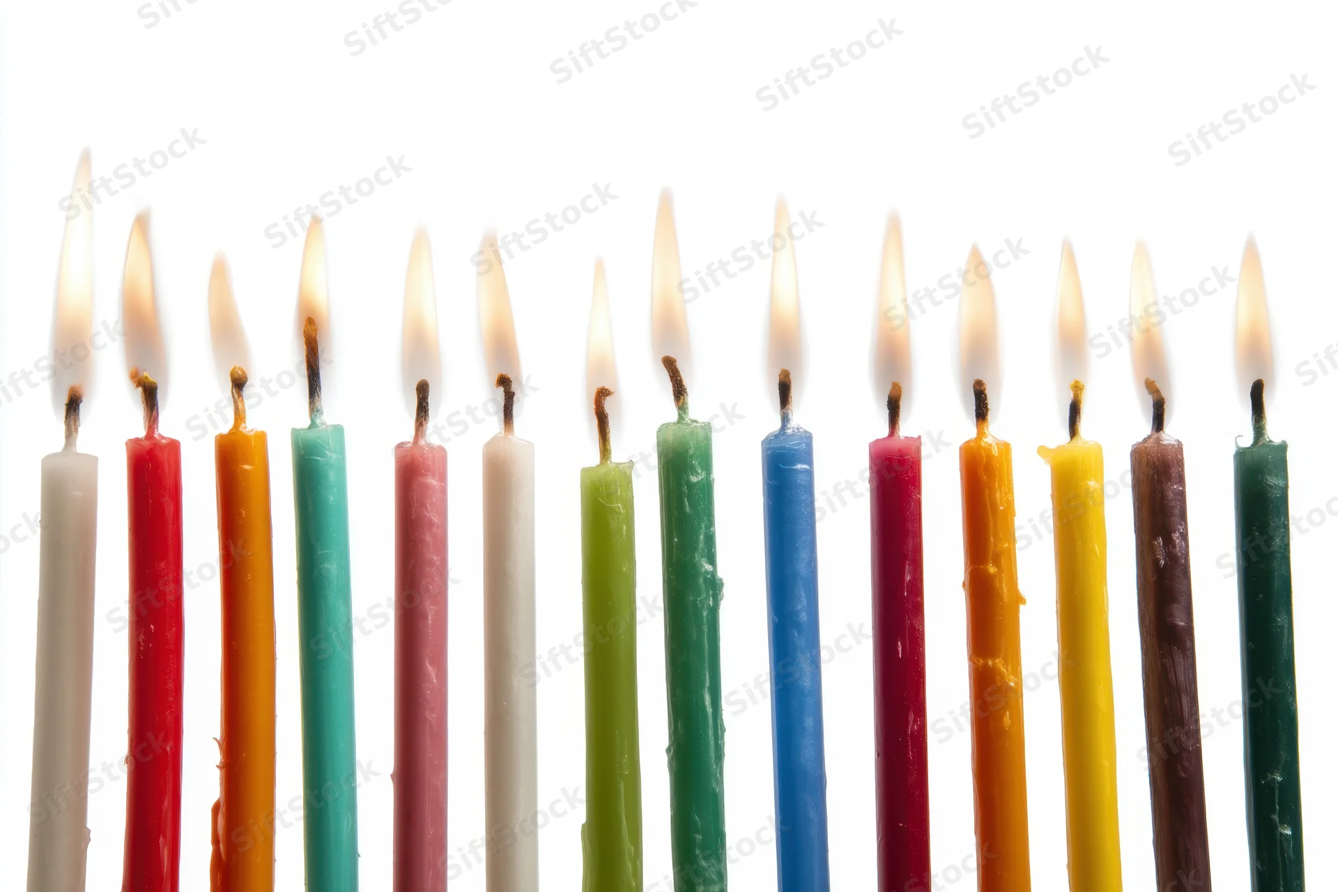 Row of tall colorful lit candles against white background