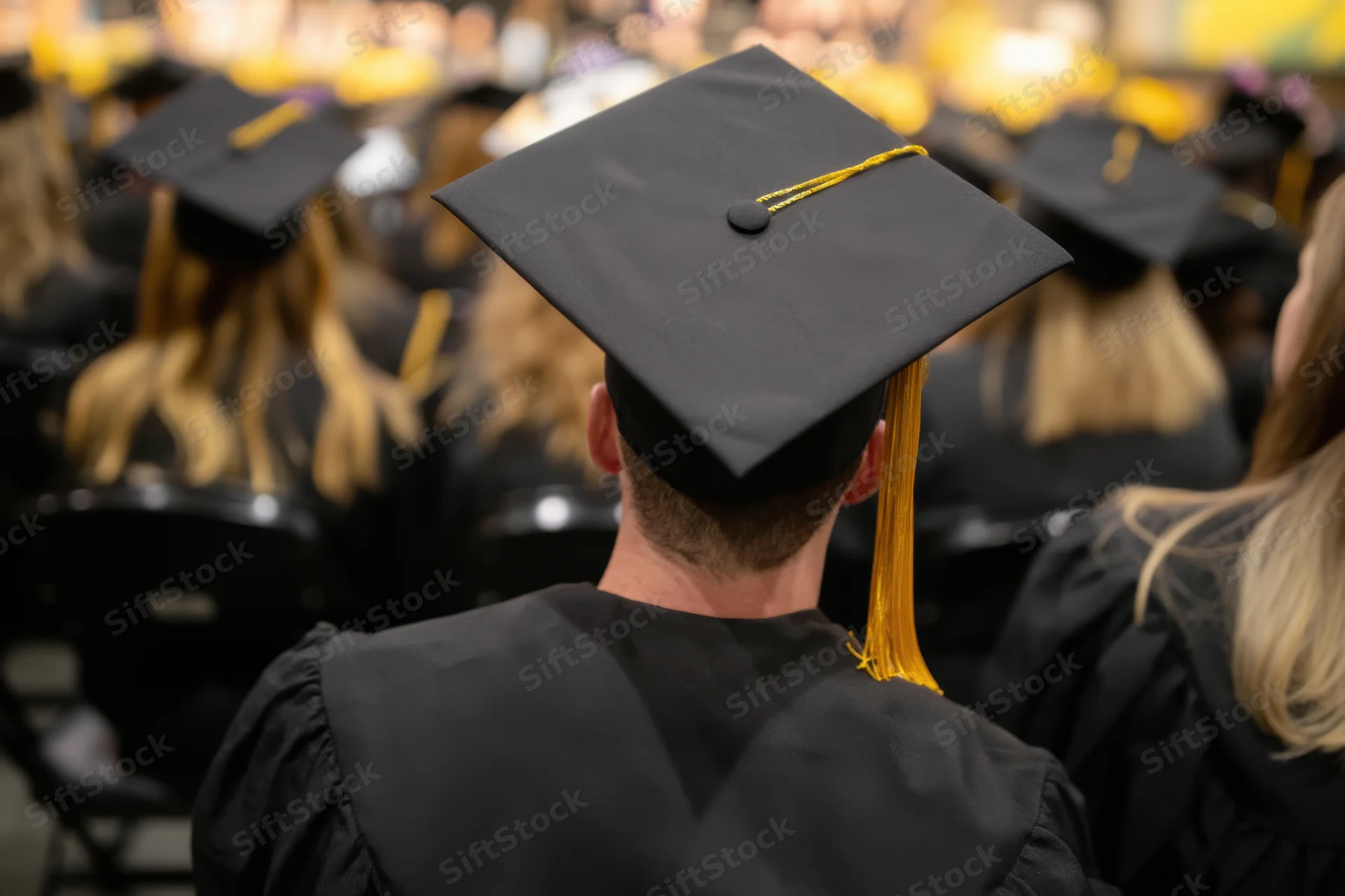 Graduate in cap and gown seated facing forward at a commencement ceremony