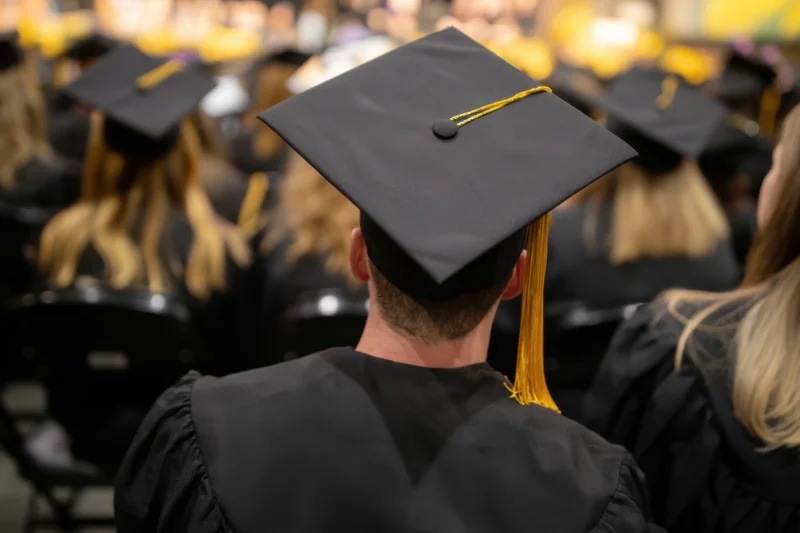 Graduate in cap and gown seated facing forward at a commencement ceremony