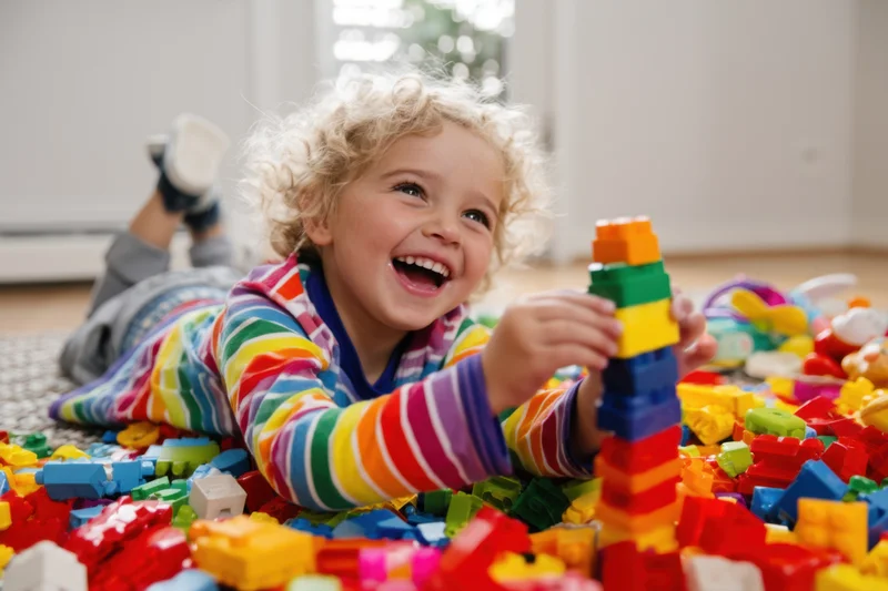 Toddler playing with colorful building blocks on floor indoors