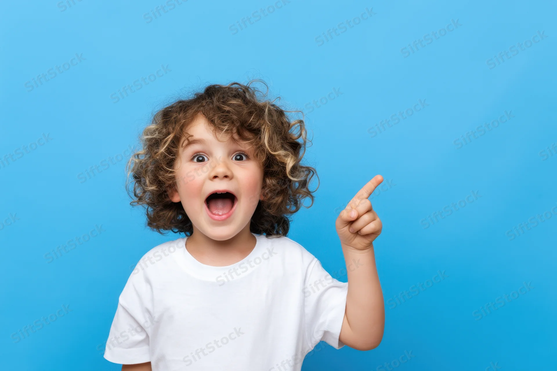 Young child with curly hair pointing upward in excitement against a blue background