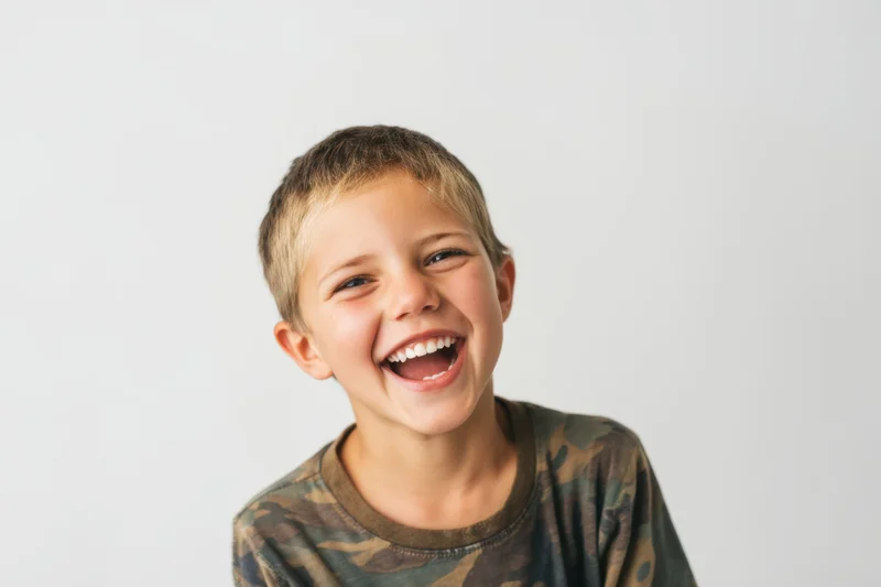 Young boy laughing with wide open smile against white background