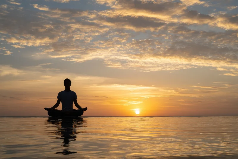 Man in meditation pose sitting on water at sunset