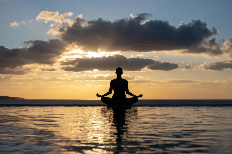 Woman meditating in lotus pose at sunset by the ocean