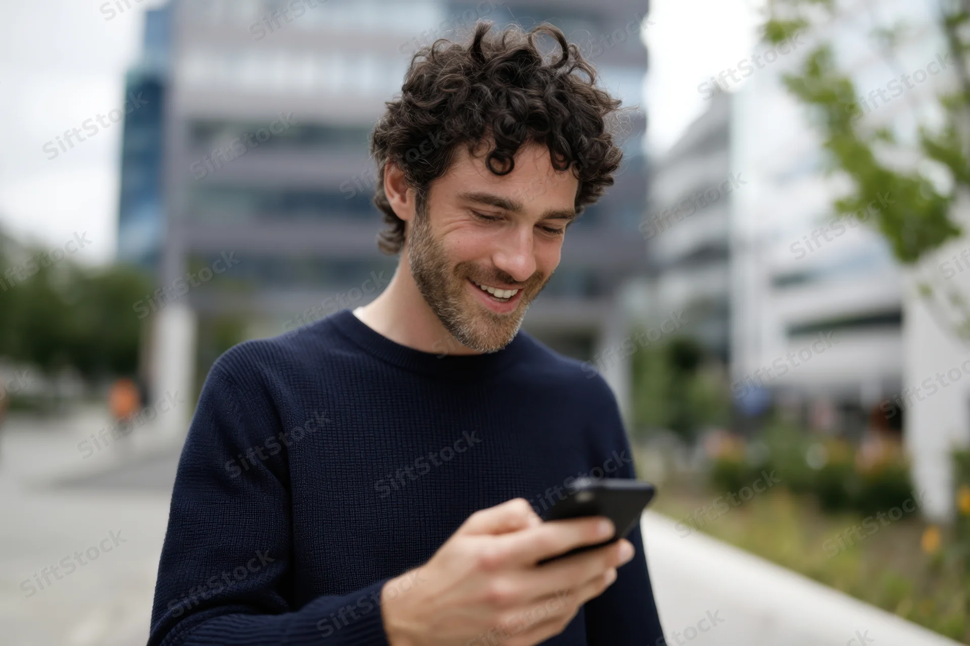 Man smiling while using smartphone outdoors in city setting