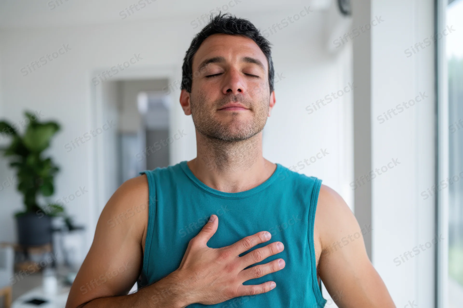 Man meditating with hand on chest in a bright home interior