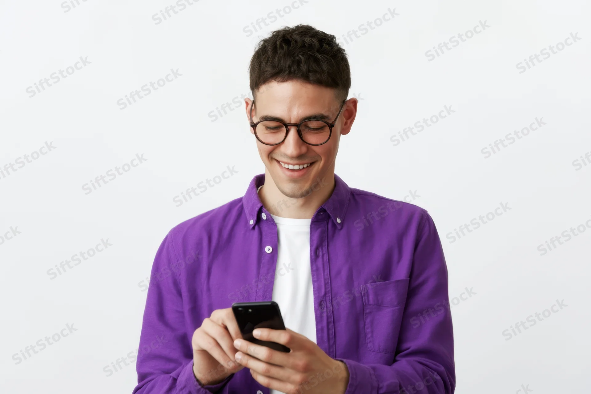 Young man smiling while texting on smartphone in studio setting