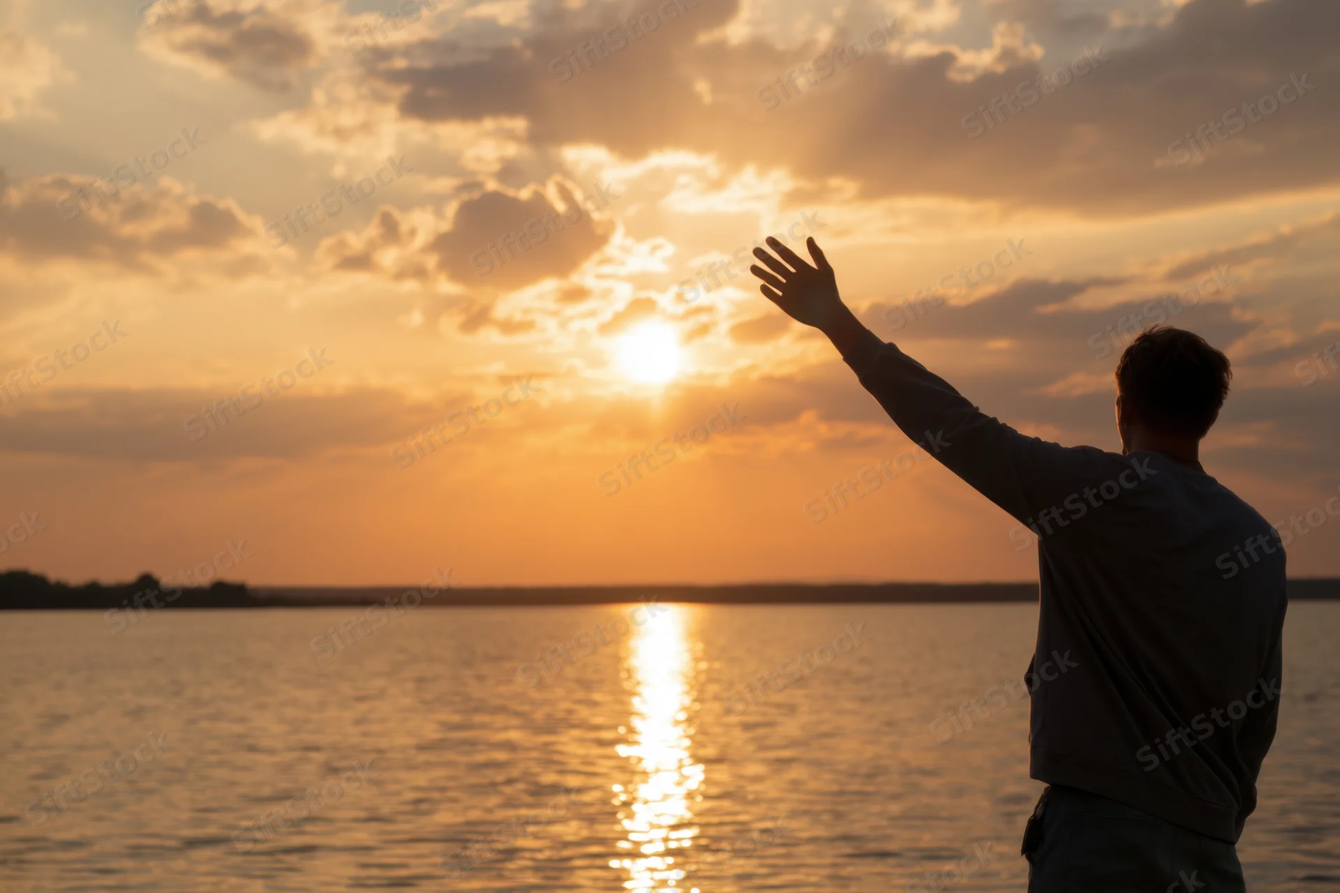 Man reaching toward sunset over ocean with hand outstretched