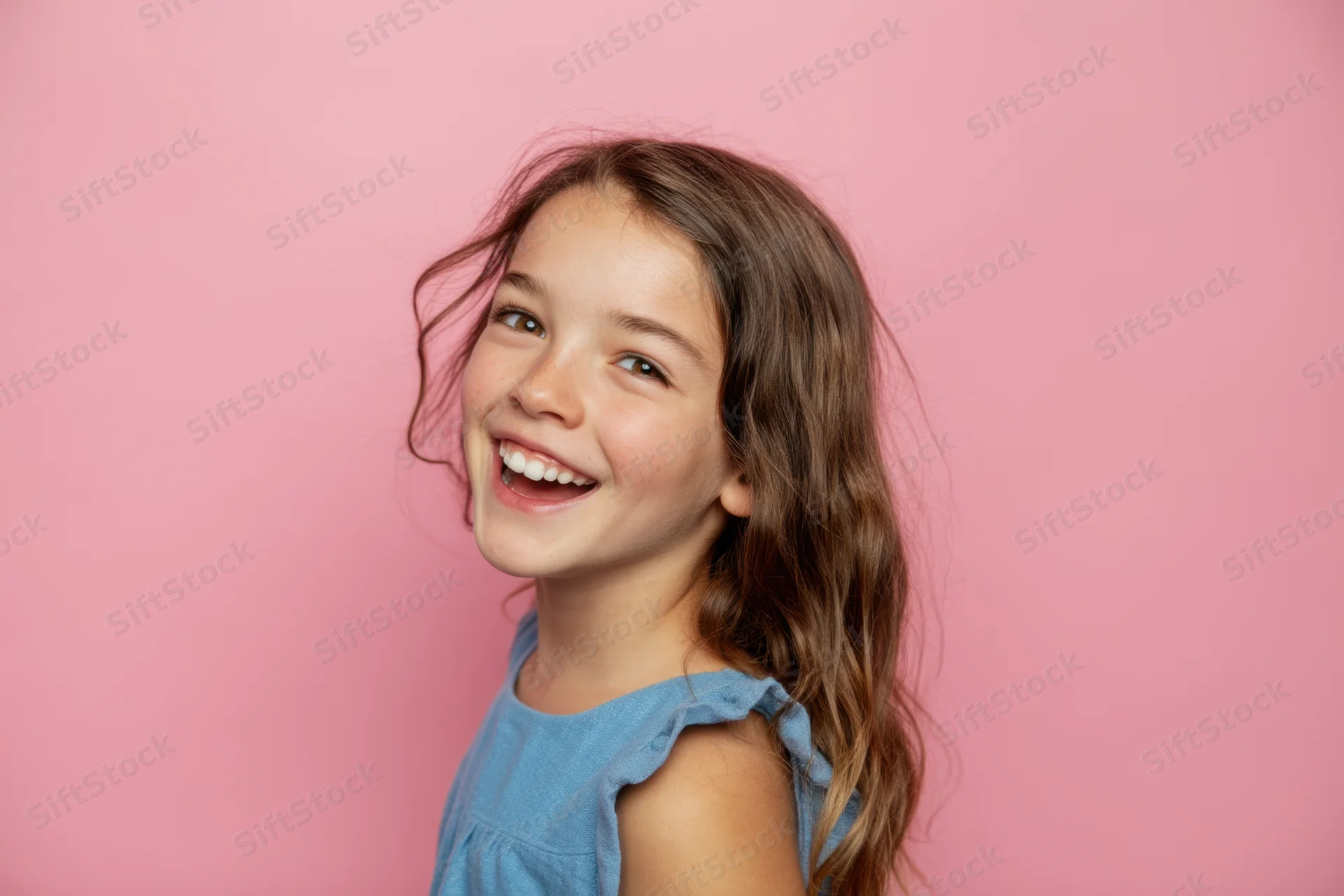 Smiling young girl in blue dress against pink background