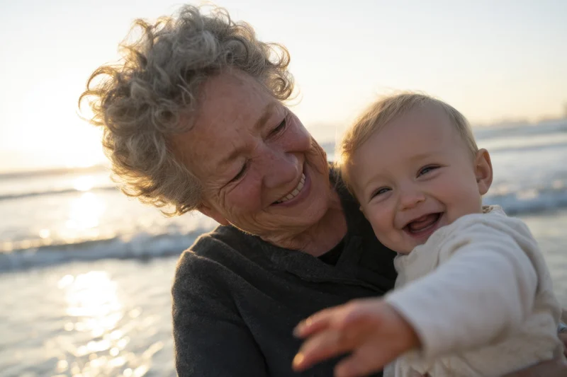 Elderly woman with short curly gray hair holds a laughing baby