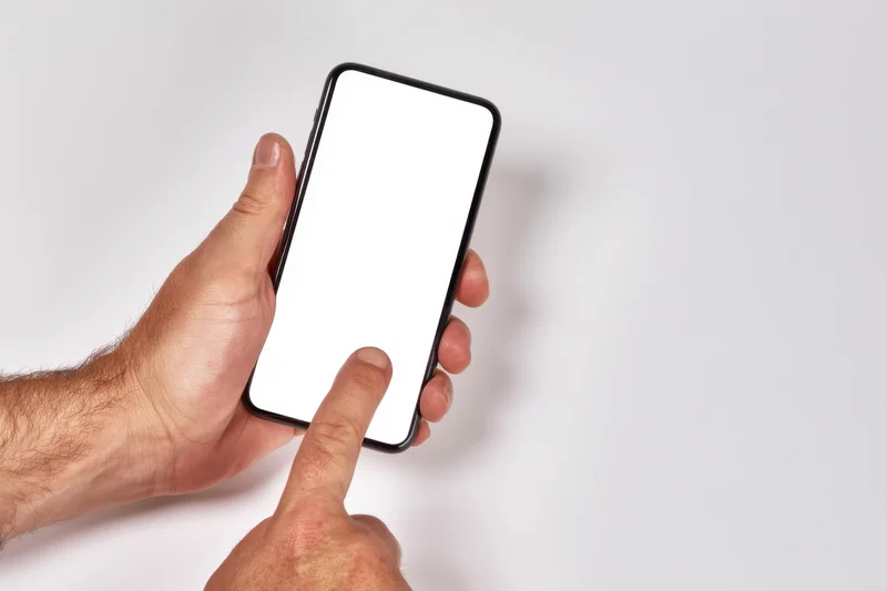 Hand holding smartphone with blank white screen, finger touching display, isolated on white background