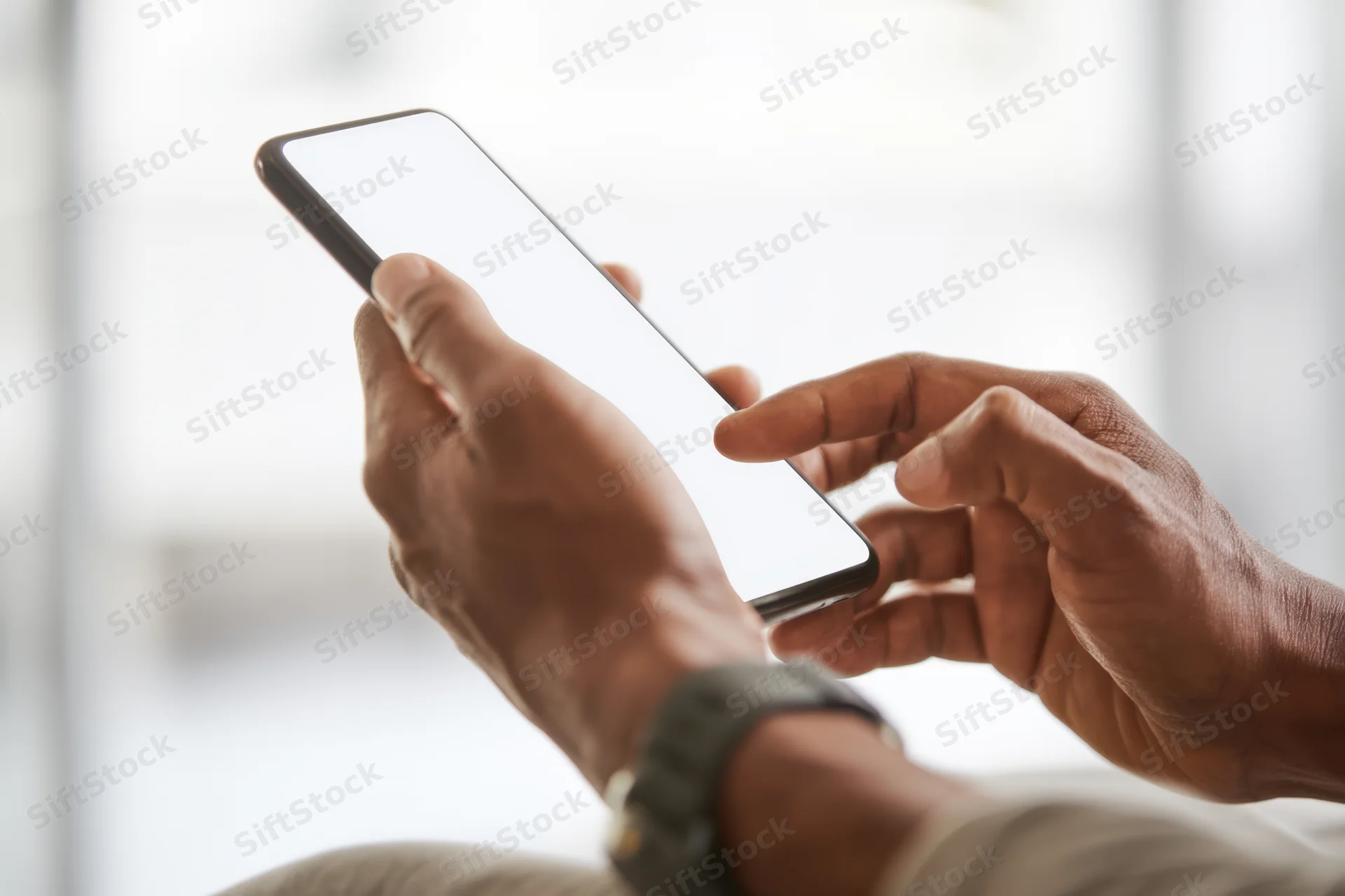 Close-up of hands holding a smartphone with blank white screen, fingers tapping the display