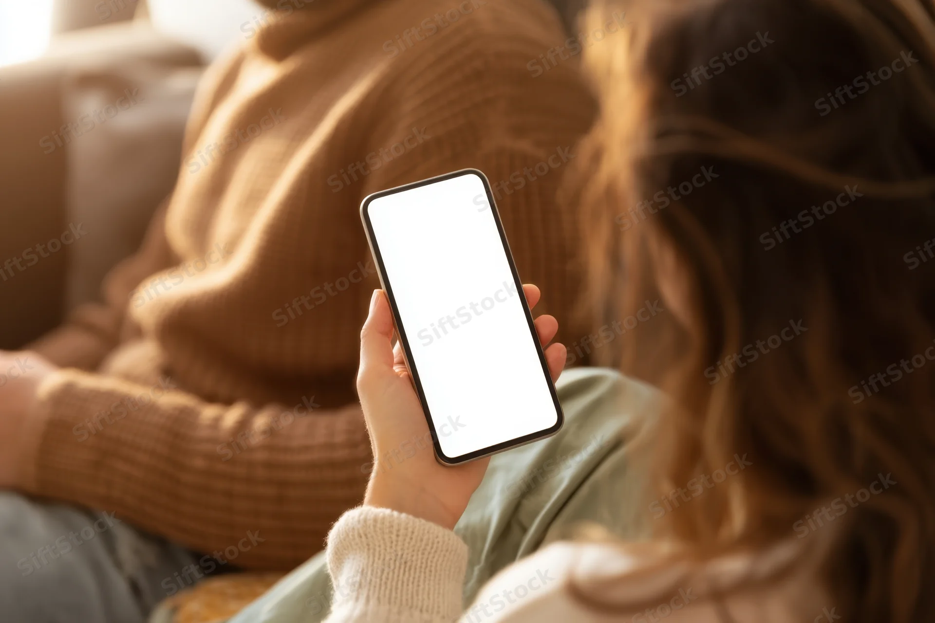 Woman holding smartphone with blank white screen in living room