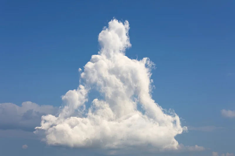 Large fluffy white cloud shaped like a meditating figure against clear blue sky