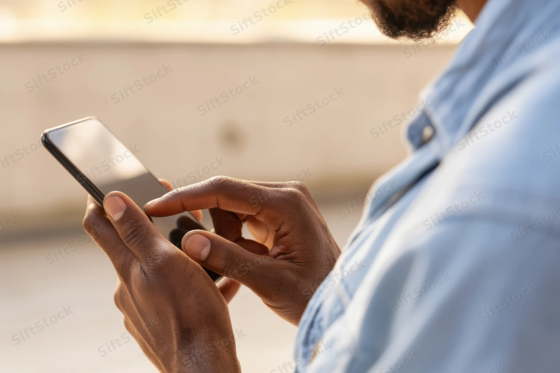 Man tapping on smartphone outdoors in light blue shirt