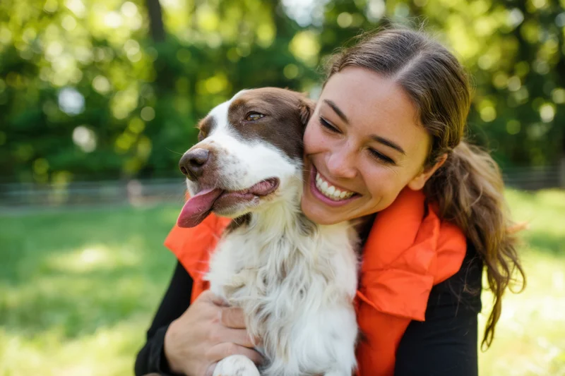 Woman smiling while hugging a dog in a park