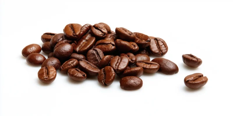 Roasted coffee beans scattered in a pile on a white background