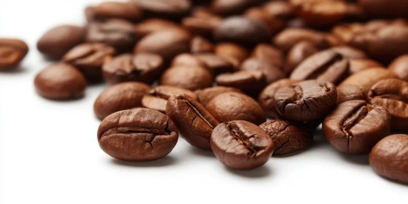 Roasted coffee beans scattered on a white surface