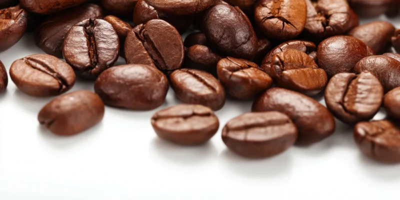 Roasted coffee beans scattered across a white surface in closeup view