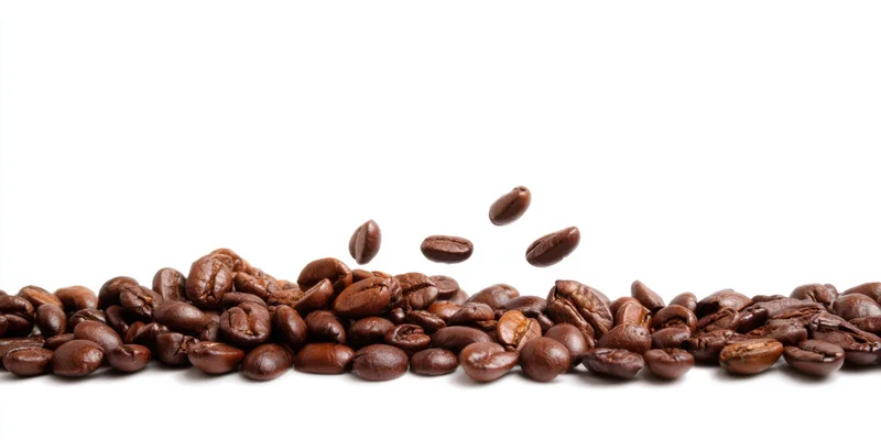 Roasted coffee beans scattered in a line with some falling mid-air on white background