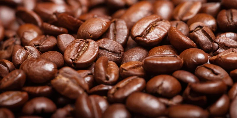 Closeup of glossy roasted coffee beans densely packed in a pile