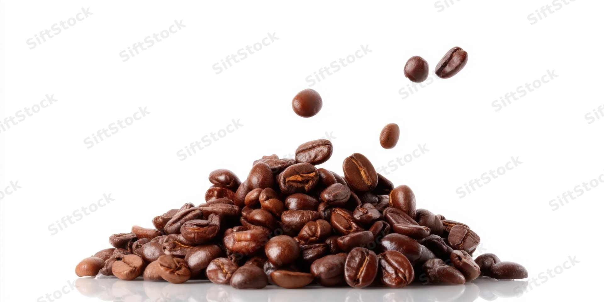 Roasted coffee beans piled on white surface with some falling into the heap